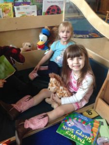 Two girls sitting with stuff animals