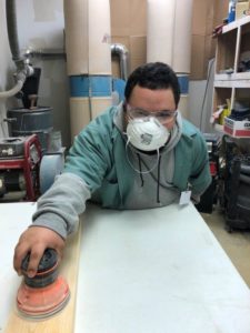 Man with face mask using a hand sander